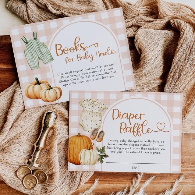 Two baby shower invitation cards with pumpkins and checkered patterns on a textured fabric background.