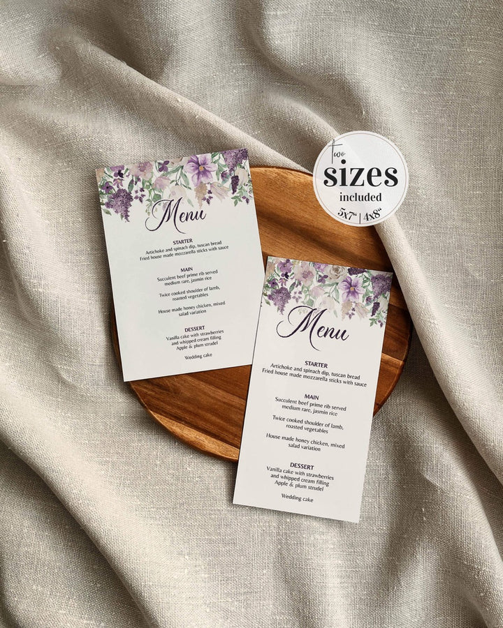 Two floral menu cards on a wooden plate with a beige fabric background