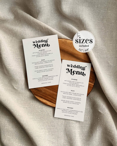 Two wedding menu cards on a wooden board with a beige fabric background